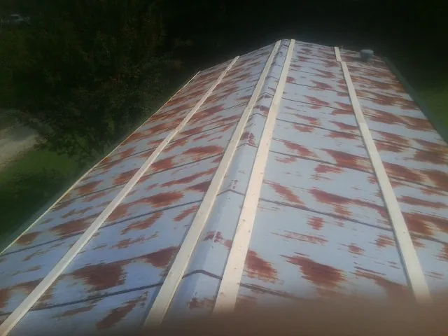 Rusted metal roof panels with new wood purlins before replacement — Storm Damage Roof Repair in Jackson Heights by Roofing Brothers