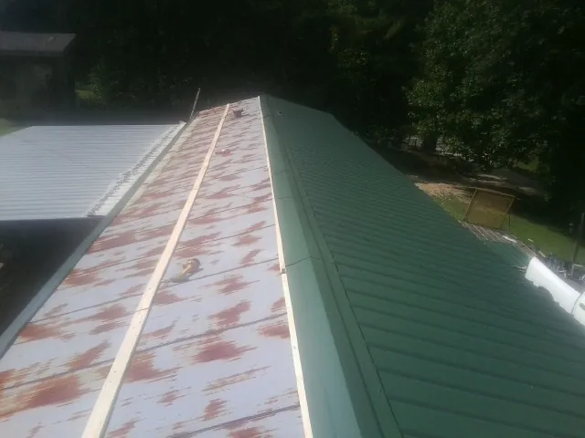 Old rusted panels beside newly installed green metal roofing — Wind Damage Roof Repair by Roofing Brothers in Jackson Heights