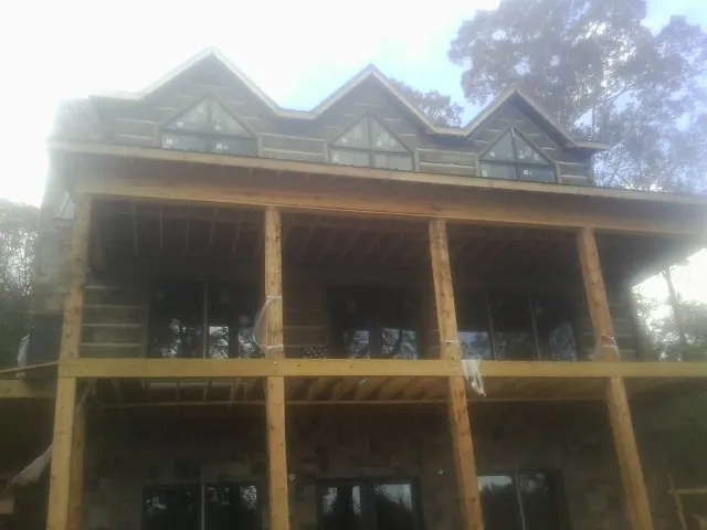Dormers and porch framing on a large log home under construction — Roof Coating work by our crew in Jackson Heights