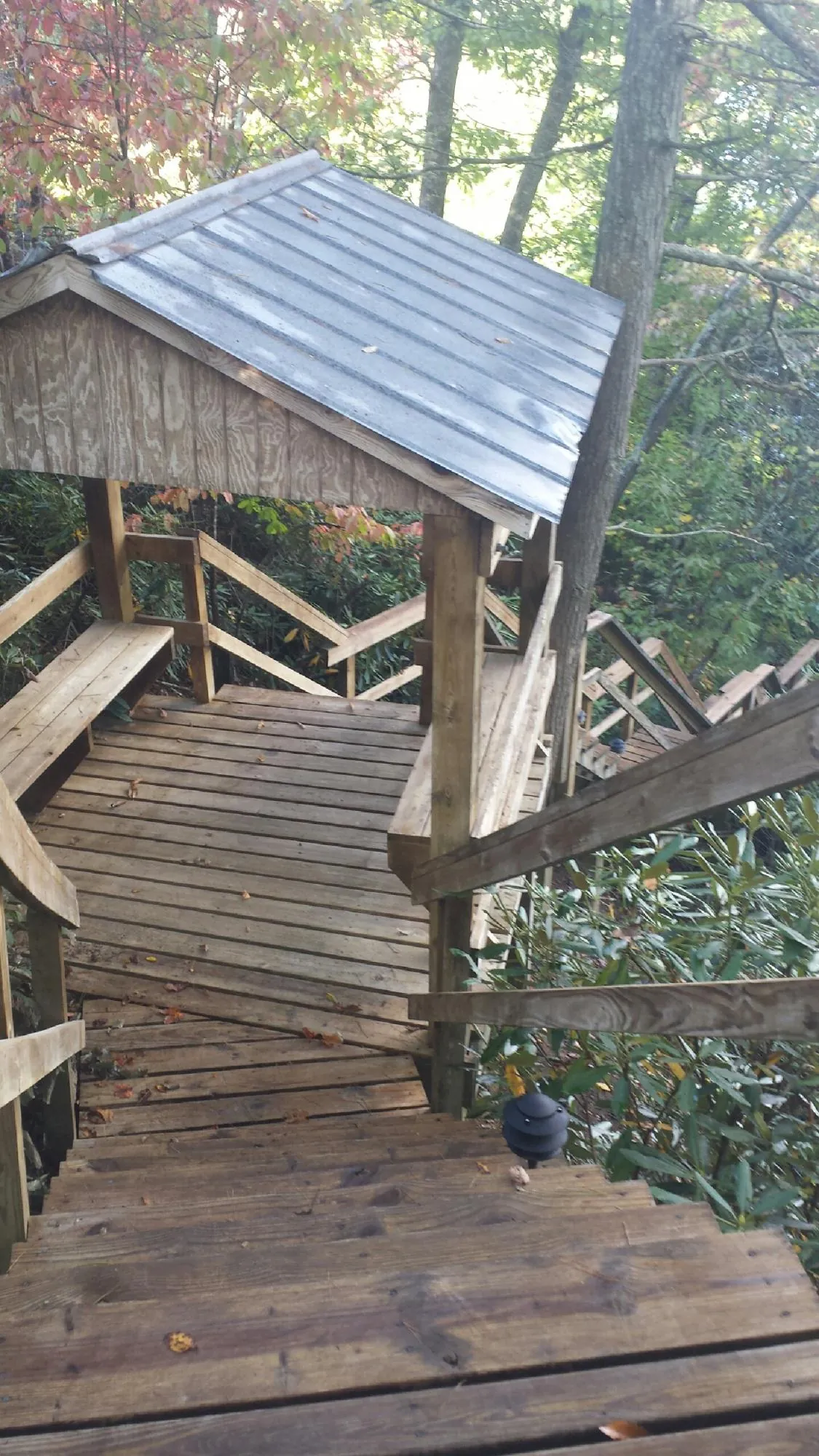 Metal roofed shelter over wooden steps on a wooded walkway — Skylight Repair & Installation work by our crew in Jackson Heights